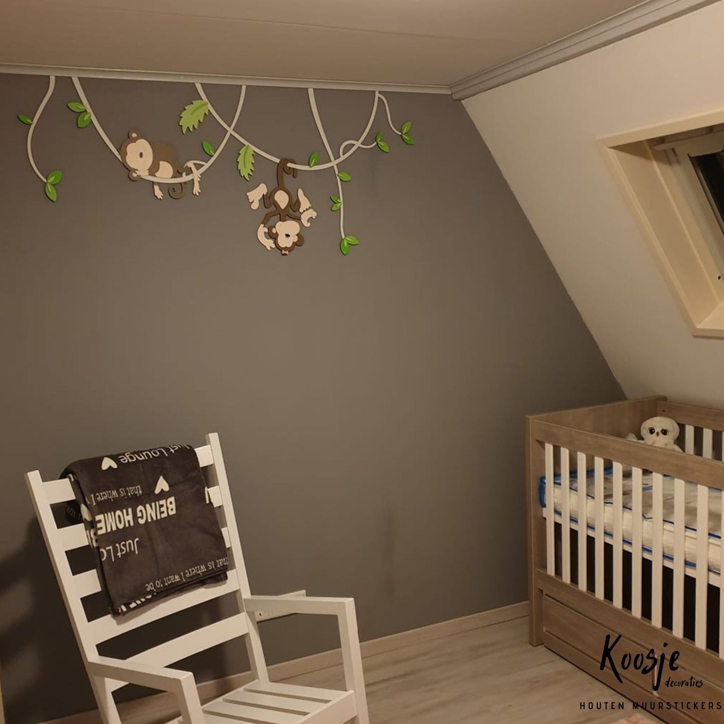Houten wanddecoratie voor kinderkamer, twee aapjes hangend aan lianen met groene bladeren, donkere muur