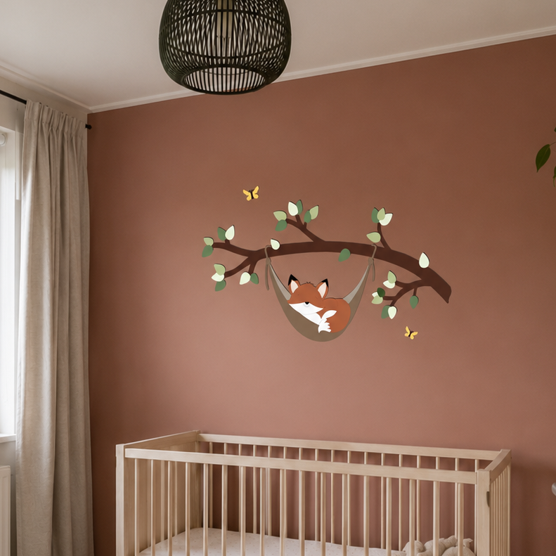 Babykamer met houten ledikant, witte commode en houten wanddecoratie van een slapend vosje in een hangmat aan een tak op roestkleurige muur.
