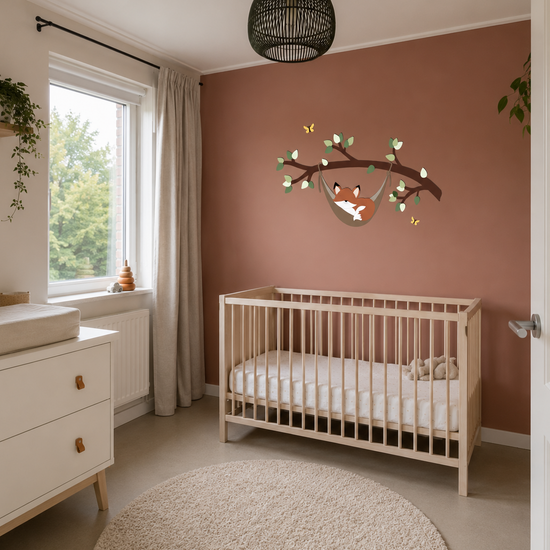 Babykamer met houten ledikant, witte commode en houten wanddecoratie van een slapend vosje in een hangmat aan een tak op roestkleurige muur.
