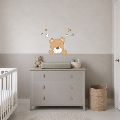 Babykamer met wit ledikant, grijze commode en muurdecoratie van een beertje met sterren in groen, wit en beige.
