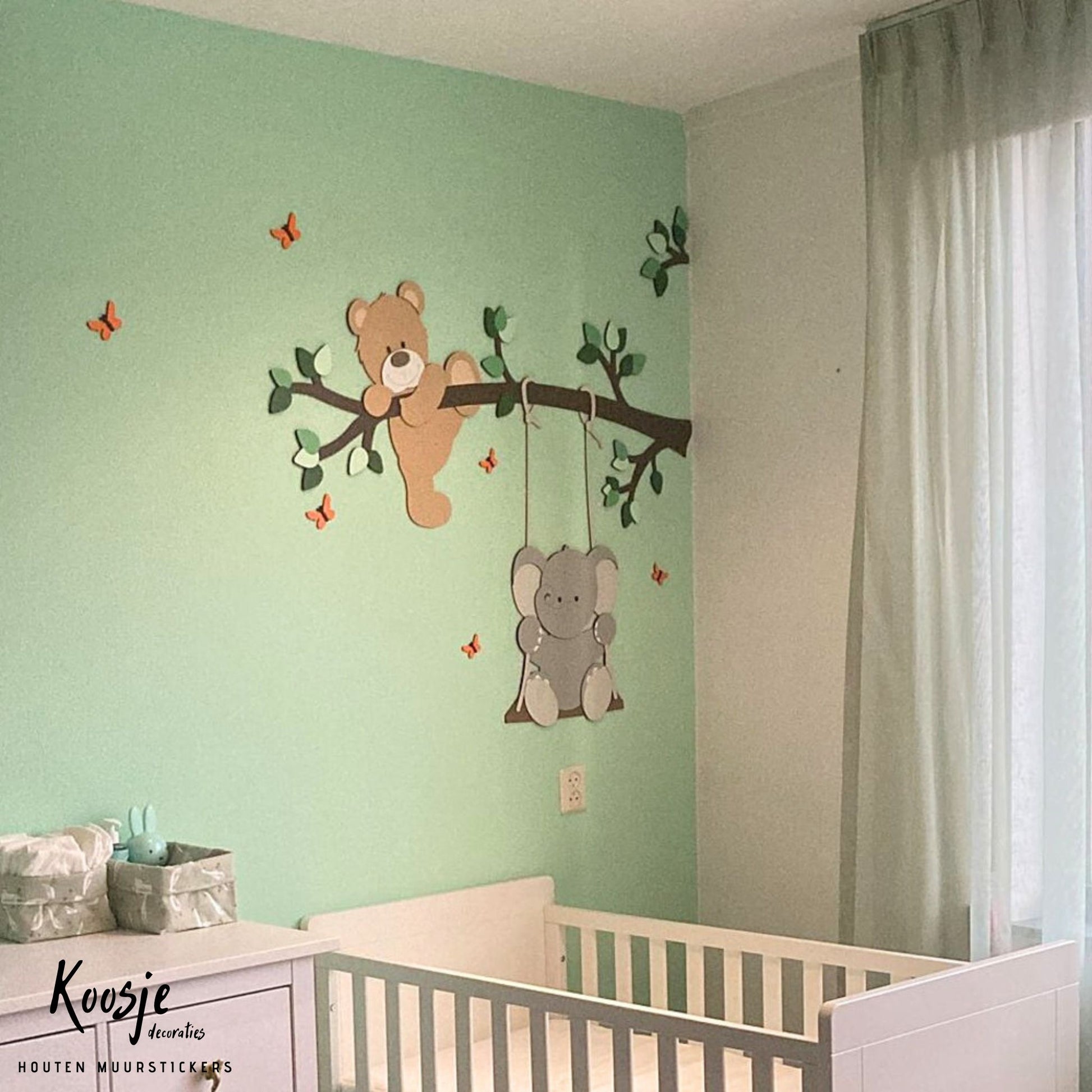 Ideeën babykamer muurdecoratie tak met klauterend beertje en schommelend olifantje op groene muur. Voor meisje en jongen
