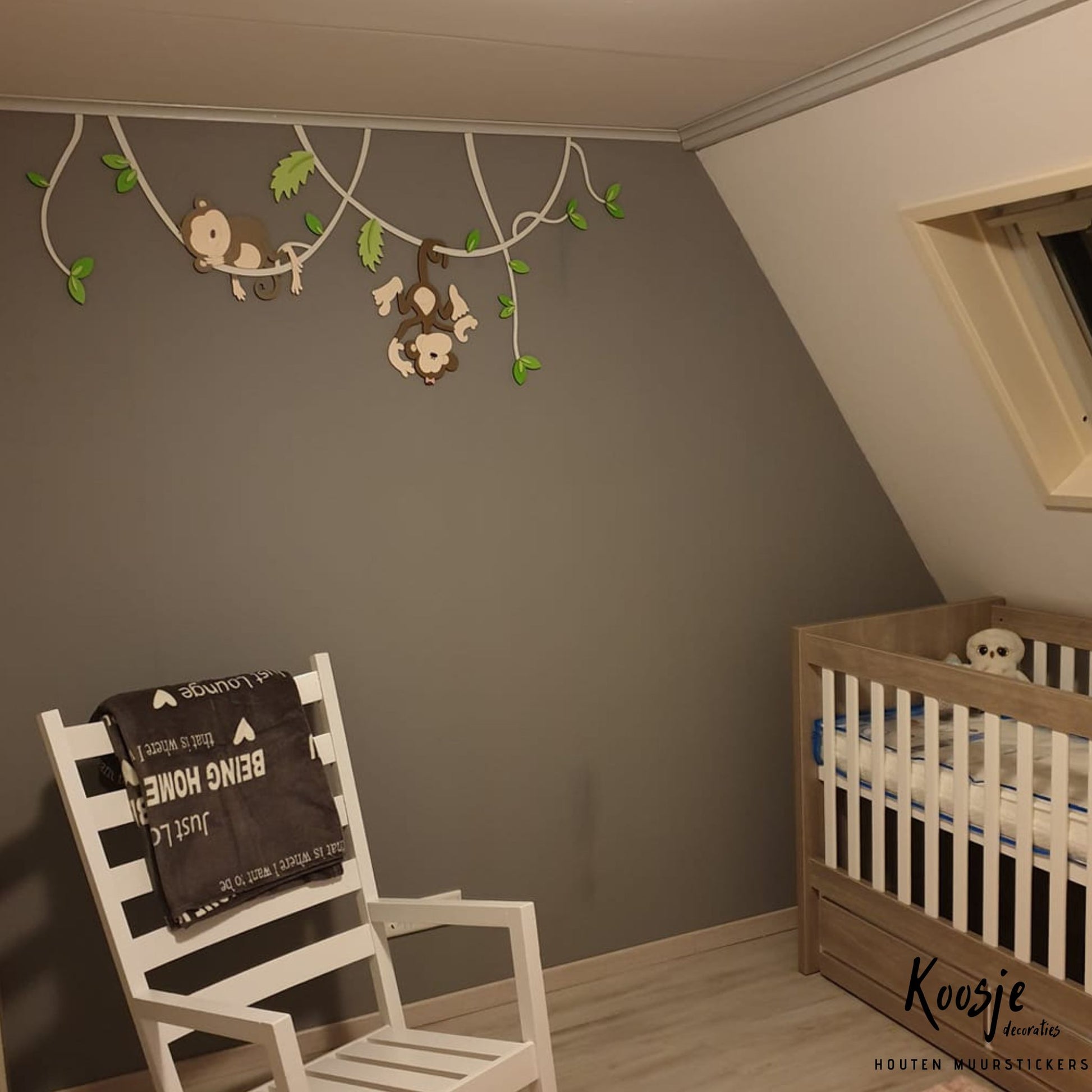 Houten wanddecoratie voor kinderkamer, twee aapjes hangend aan lianen met groene bladeren, donkere muur