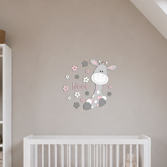 Houten wanddecoratie van girafje omringd door bloemen, op een meisje babykamer met witte meubels en beige wand.