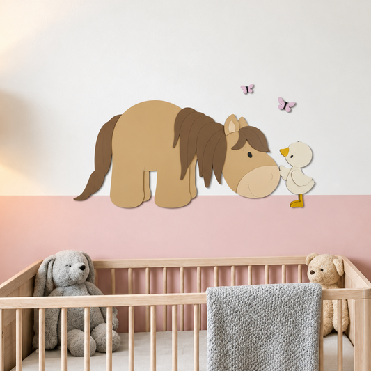 Houten muurstickers van een beige paard met chocoladebruine manen en een gansje, boven een houten ledikant in een babykamer met roze lambrisering.
