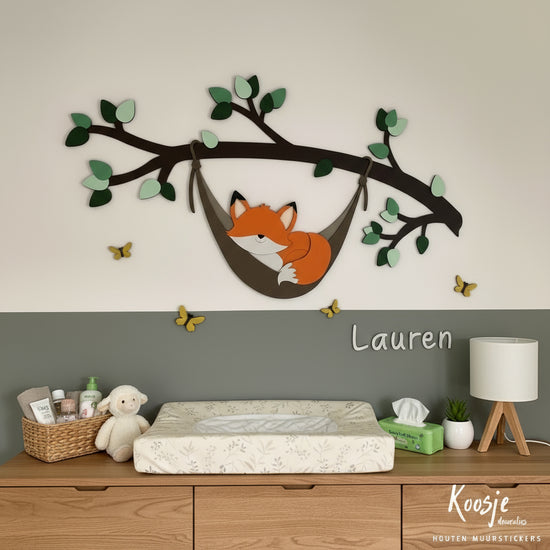 Houten muurdecoratie babykamer – tak met groene bladeren en slapend vosje in hangmat