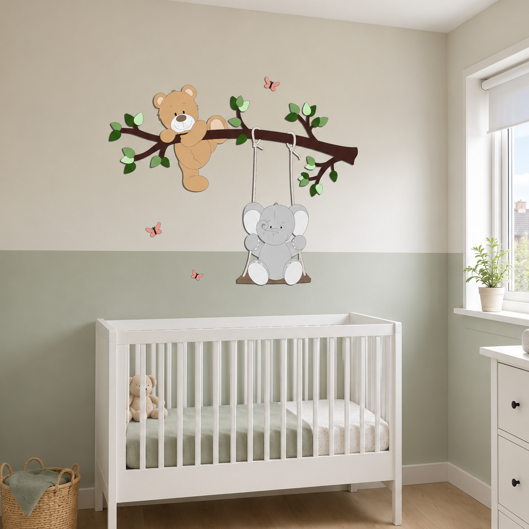 Witte babykamer met houten muurstickers van een beer op een tak en een olifant op een schommel, boven een wit ledikant. De muur is tweekleurig in beige en zacht groen, met roze vlinders en een commode naast het raam.
