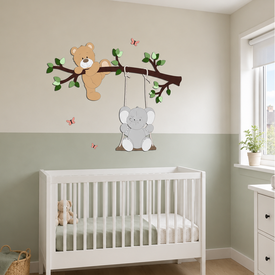 Witte babykamer met houten muurstickers van een beer op een tak en een olifant op een schommel, boven een wit ledikant. De muur is tweekleurig in beige en zacht groen, met roze vlinders en een commode naast het raam.
