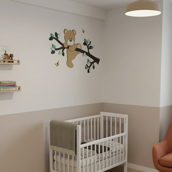 Houten decoratie babykamer met tak, groene bladeren en klauterend beige beertje boven groene lambrisering