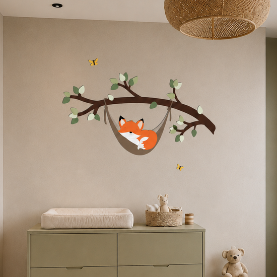 Babykamer met houten ledikant, olijfgroene commode en houten wanddecoratie van een slapend vosje in een hangmat aan een tak.
