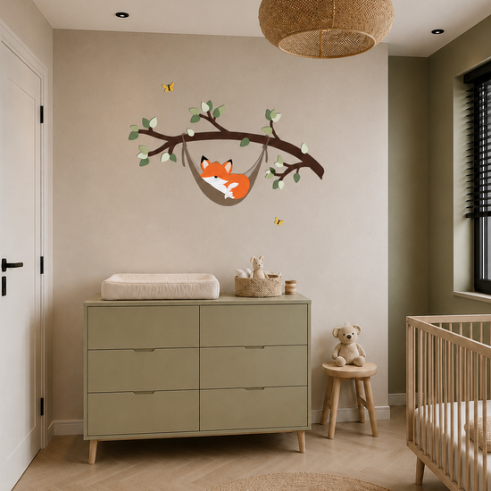 Babykamer met houten ledikant, olijfgroene commode en houten wanddecoratie van een slapend vosje in een hangmat aan een tak.