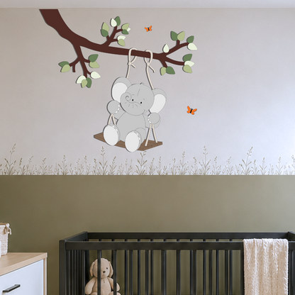 Gezellige babykamer met zwarte meubels en groene lambrisering op de muur. Aan plafond tak met groene bladeren muurdecoratie, met schommelend olifantje eraan.