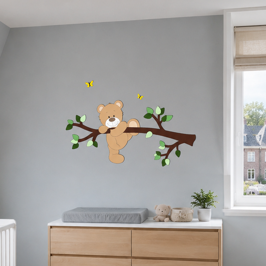 Muurdecoratie kinderkamer donkerbruine tak met groene bladeren en een klauterend beige beertje op muur in oudblauw. 