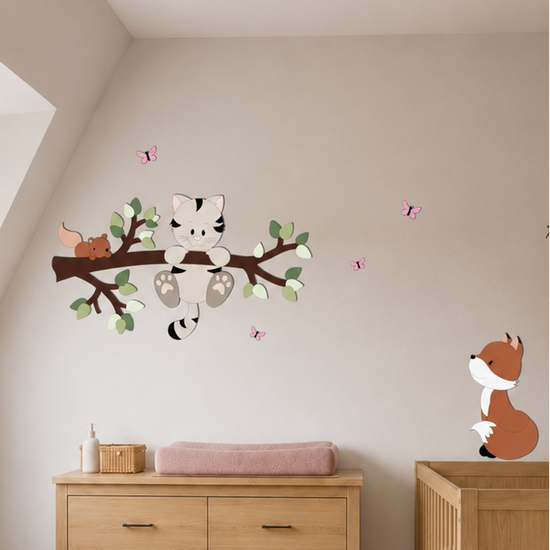 Houten muurstickers in een sfeervolle babykamer met naturel en oudroze tinten.
Een poesje zit op een tak met blaadjes, omringd door vlinders en een eekhoorntje.
Naast de commode staat een vosje als speelse houten muurdecoratie bij het ledikant.
Inspiratie voor een babykamer met houten wanddecoratie in een bosdieren thema.
