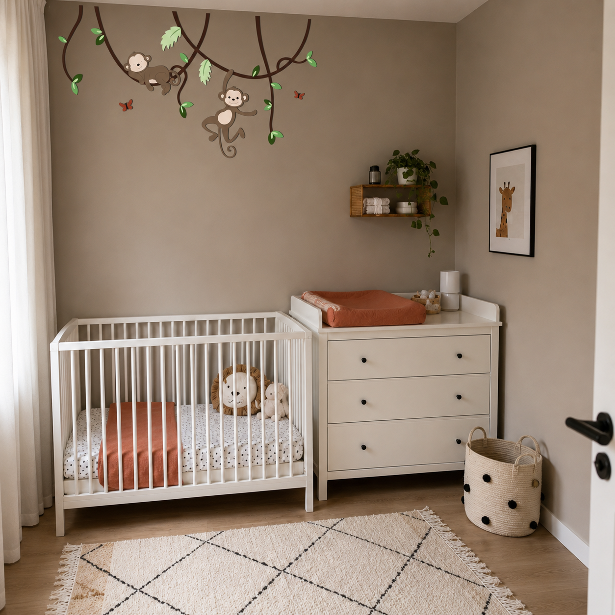 Babykamer met wit ledikant en commode tegen een taupekleurige muur, gedecoreerd met houten takken en speelse aapjes.
