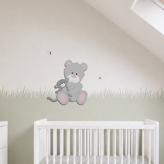 Licht ingerichte babykamer met houten muurdecoratie van een grijze beer met knuffel, sagegroene muur en oudroze accessoires.