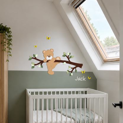 Houten muurdecoratie van een tak met klauterend beertje, boven een groene lambrisering op een babykamer.