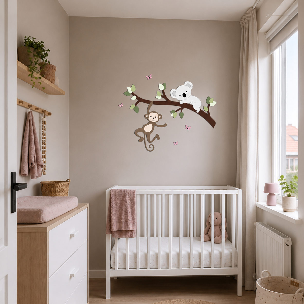 Babykamer in oudroze met witte meubels en wanddecoratie van tak met koala en aapje.