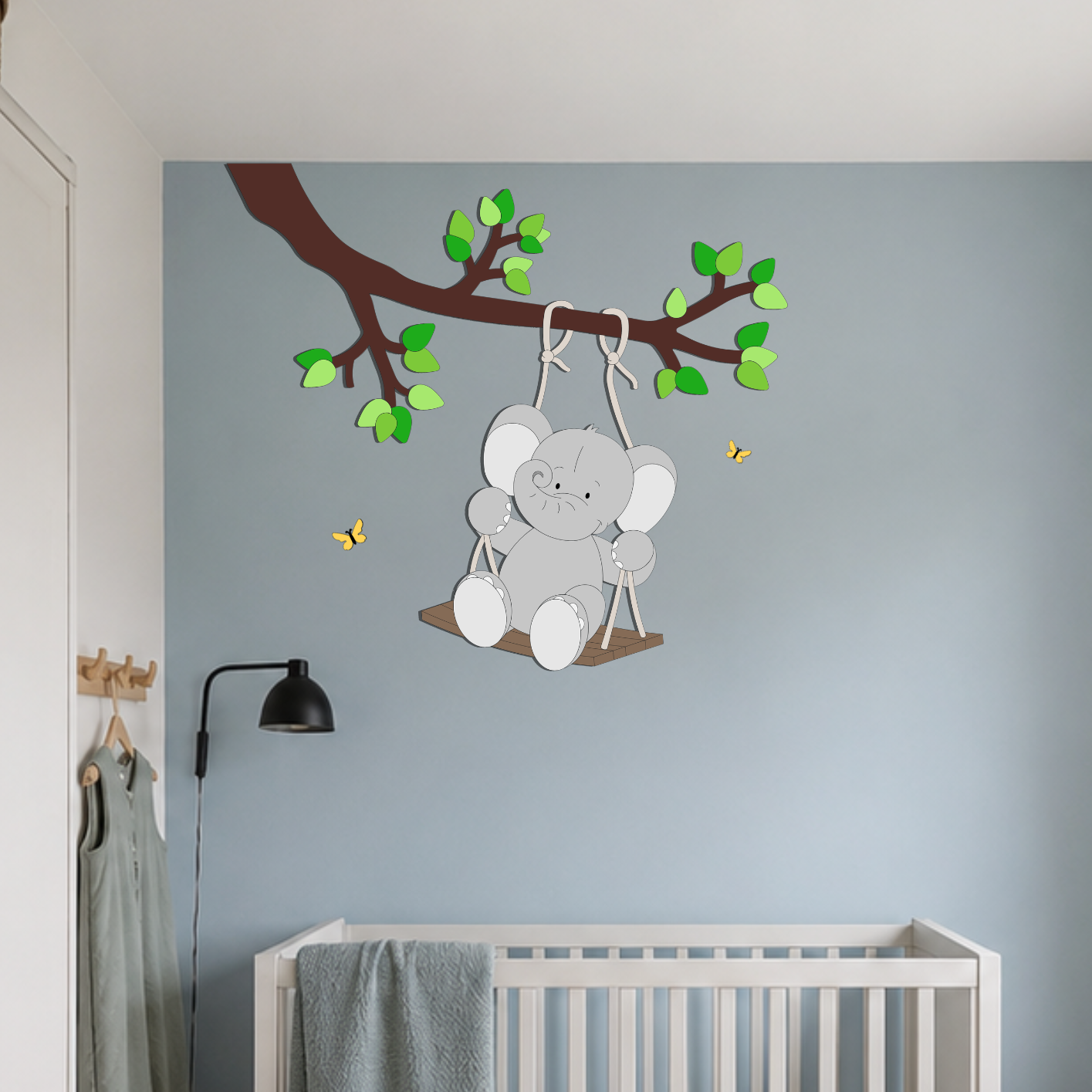 Babykamer met blauwe muur en witte meubels. Muurdecoratie van tak met olifantje op schommel.